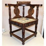 A robust antique oak corner chair with carved deco