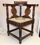 A robust antique oak corner chair with carved deco