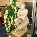 A resin ornamental garden figure of kneeling nude