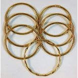 Six plain 9ct gold bangles twinned with one yellow