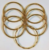 Six plain 9ct gold bangles twinned with one yellow