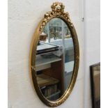 A decorative oval gilt mirror 26in