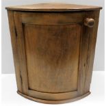 An antique curved oak corner wall cabinet with doo