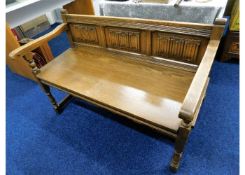 An Old Charm oak settle with linen fold decor to b