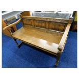 An Old Charm oak settle with linen fold decor to b