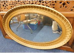 A large antique gilt framed oval mirror 46in wide