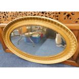 A large antique gilt framed oval mirror 46in wide