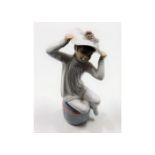 A Lladro porcelain figure of seated child with hat