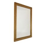 Modern gilt-framed wall mirror with bevelled rectangular plate in fluted surround, 107cm x 75cm