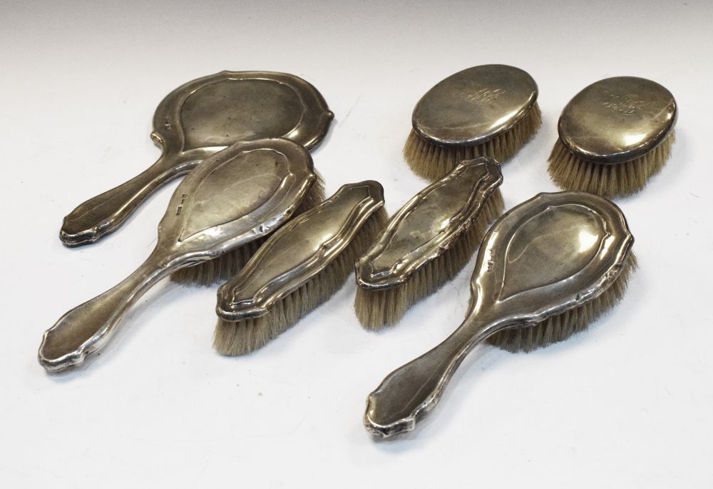 Set of five George V silver-backed dressing table items comprising hand mirror, pair of hand brushes