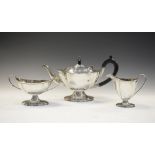 George V silver three piece tea service of serpentine outline and oval form, comprising pedestal tea