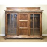 Early 20th Century carved walnut bookcase having carved strapwork frieze, fitted two glazed doors on