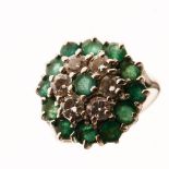 White metal, emerald and diamond cluster ring of flower head design with central emerald, six