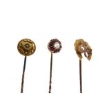 Three assorted gold and yellow metal stickpins, one with central white sapphire within border of