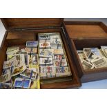 Two early 20th Century oak boxes containing a selection of postcards and cigarette cards