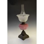 Late 19th/early 20th Century oil lamp having pink glass reservoir and pierced and square metal base,