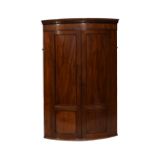 Early 19th Century inlaid mahogany bowfront corner cupboard, the moulded dentil cornice over