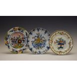 Three 19th Century tin-glazed earthenware plates, each with polychrome floral decoration, largest