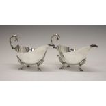 Pair of George V silver sauce boats, with shaped rim and standing on tripod hooved feet, sponsors