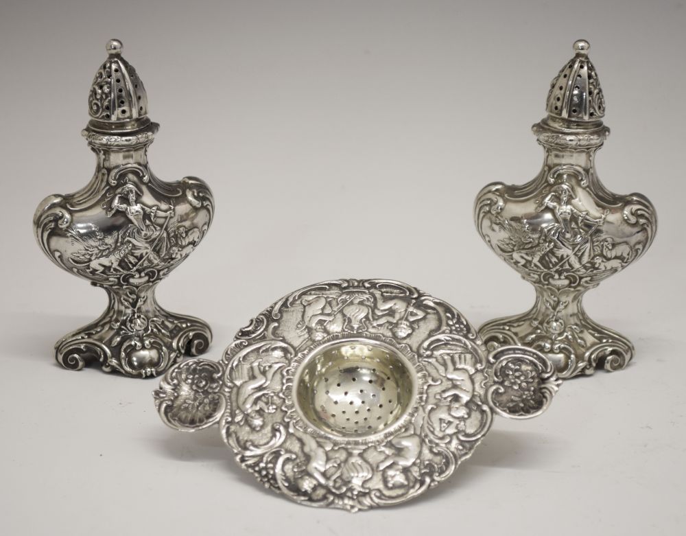 Pair of Continental white metal pepperettes, each of rococo urn form having repousse decoration of a