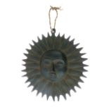 Cast iron wall plaque, of sunburst design, with convex mask framed by sunburst, 17.5cm diameter