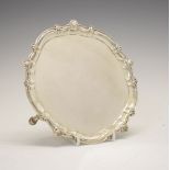 Victorian silver card tray, of pie-crust form with shell ornaments on three hoof feet, London