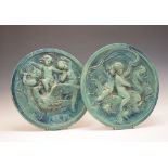 Pair of late 19th Century green-glazed majolica plaques, each of circular form with cavorting