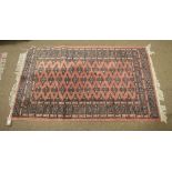 Three machine-made wool rugs of matching design with gul-decorated pink ground, largest 97cm x