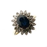 Yellow metal, sapphire and diamond cluster ring, the central faceted oval sapphire within a border