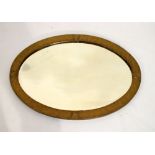 Art Nouveau style early 20th Century hammered brass finish oval framed bevelled glass mirror, 68.5cm