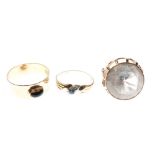 Three assorted yellow metal rings comprising a broad band ring with oval cabochon, dress ring set