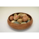 Collection of polished geological specimen stone eggs in a turned wooden bowl