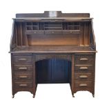 Early 20th Century stained oak roll top desk, the tambour front enclosing a drawered and pigeon