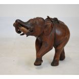 Large carved wooden figure of an elephant with one foreleg raised, 37cm high