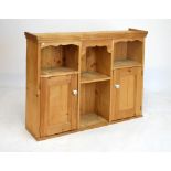 Stripped pine cabinet with wavy valance over four recesses and two cupboards, 121cm wide x 98cm high