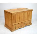 Pine mule chest with hinged cover and planked front over two drawers on wavy base, 123cm wide