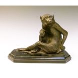 Reproduction bronzed figure of a seated monkey on ebonised base, 14cm high