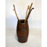 Oak barrel stickstand with a quantity of rustic walking sticks, the barrel standing 52cm high