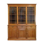 Early 20th Century walnut library bookcase, the moulded cornice over three glazed doors with