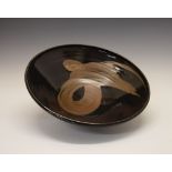 Chris Carter (1945-) - Large studio pottery tenmoku glazed footed bowl, having brown swirled iron