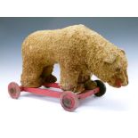 Large early 20th Century golden mohair bear (possibly Steiff), on a red wooden frame with wheels,