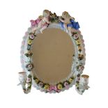Early 20th Century porcelain wall mirror having twin putto surmounts holding a floral garland on
