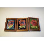 Three Moorcroft rectangular pot lids, each decorated with flowers, framed, 15cm x 12cm overall