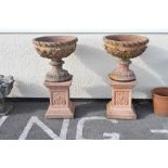 Pair of terracotta-coloured reconstituted garden urns, each with hemispherical bowl on spirally-