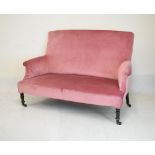 Late Victorian settee raised on ebonised turned front supports upholstered in pink fabric, 145cm