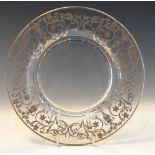 20th Century glass plate with white metal overlay of classical decoration, marked Sterling, 26.5cm