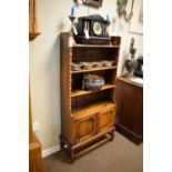 Early 20th Century oak waterfall bookcase fitted three shelves with cupboards below, 69cm wide