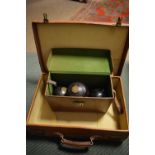 Vintage tan leather suitcase, 51cm wide, together with a cased part set of lawn bowls