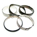 Five assorted silver and white metal bangles to include two 'snap' examples (5)