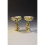 Two German porcelain pedestal baskets, having floral decoration with cherub swinging from a tree,